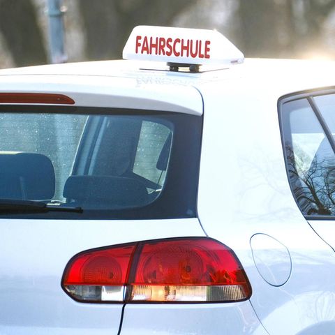Fürherschein-Quiz Führerschein-Quiz: Ein weißer VW mit ikonischem "Fahrschule"-Schild steht im Verkehr
