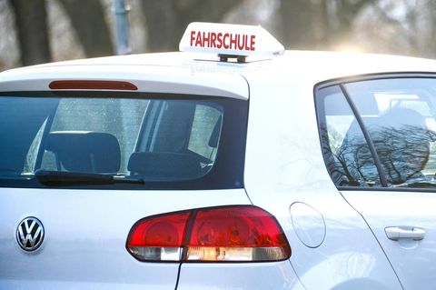 Führerschein-Quiz: Ein weißer VW mit ikonischem "Fahrschule"-Schild steht im Verkehr