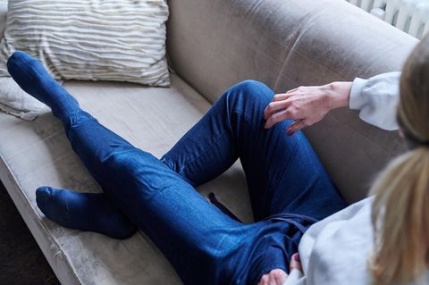 Eine Frau liegt auf einem Sofa und schaut aus dem Fenster – Symbolbild Alleinlebende