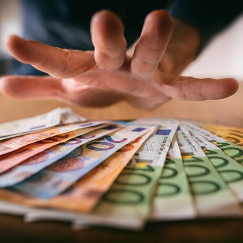 Influencer: Hand greift nach Geldscheinen