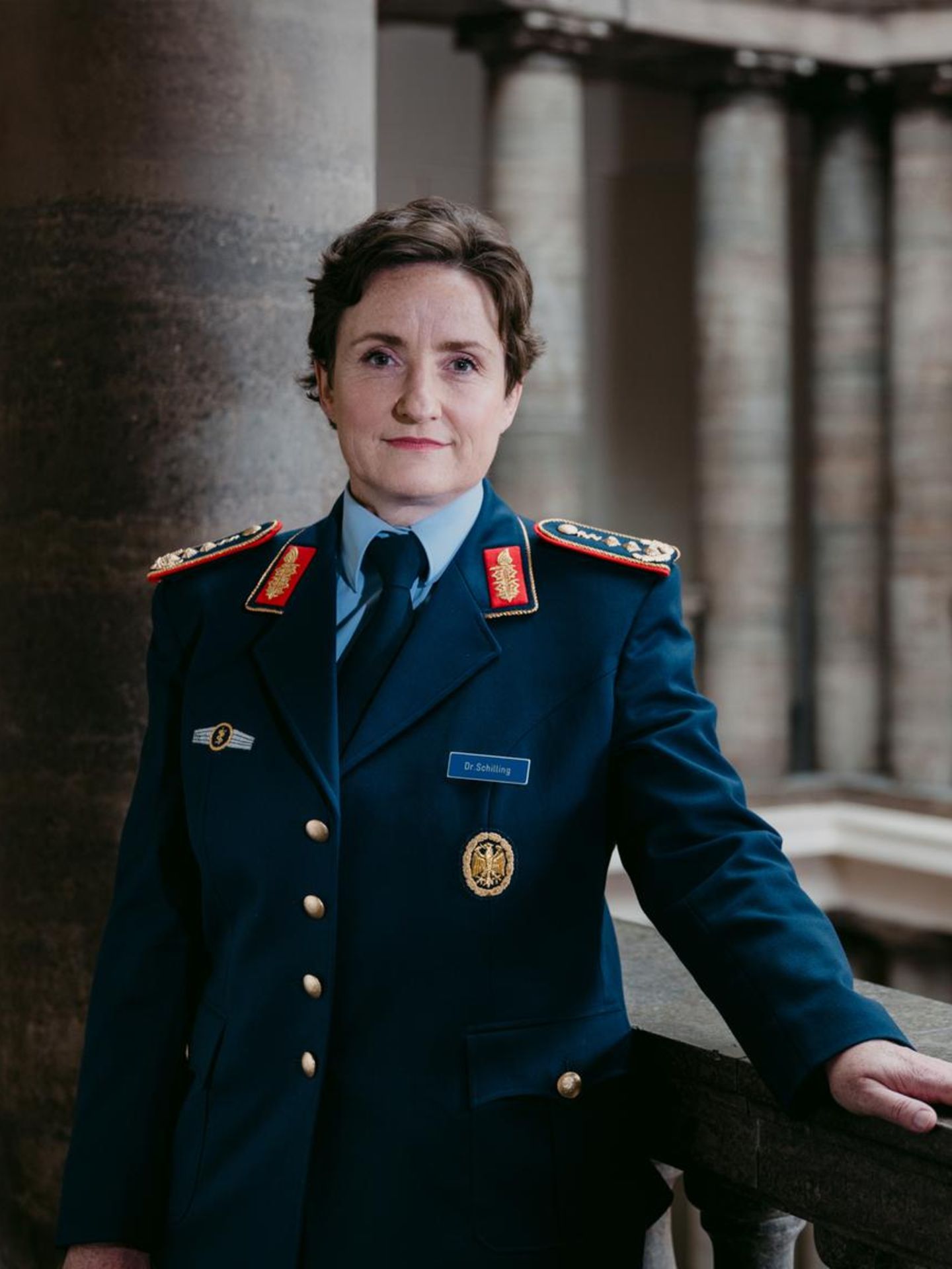 General Schilling steht an Geländer in einem Säuensaal