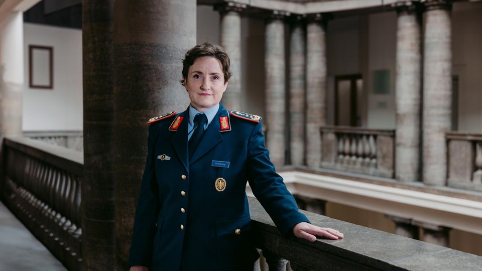 General Schilling steht an Geländer in einem Säuensaal