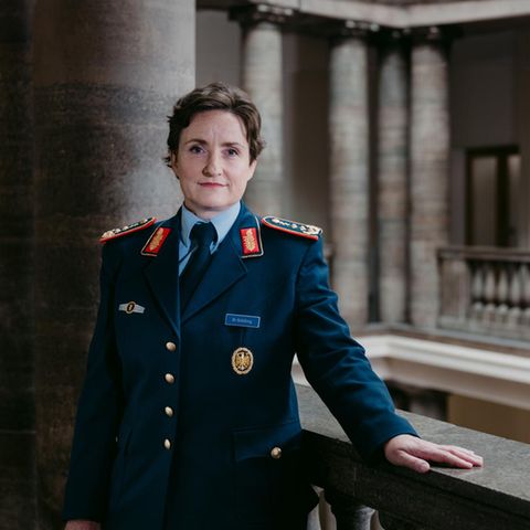 General Schilling steht an Geländer in einem Säuensaal
