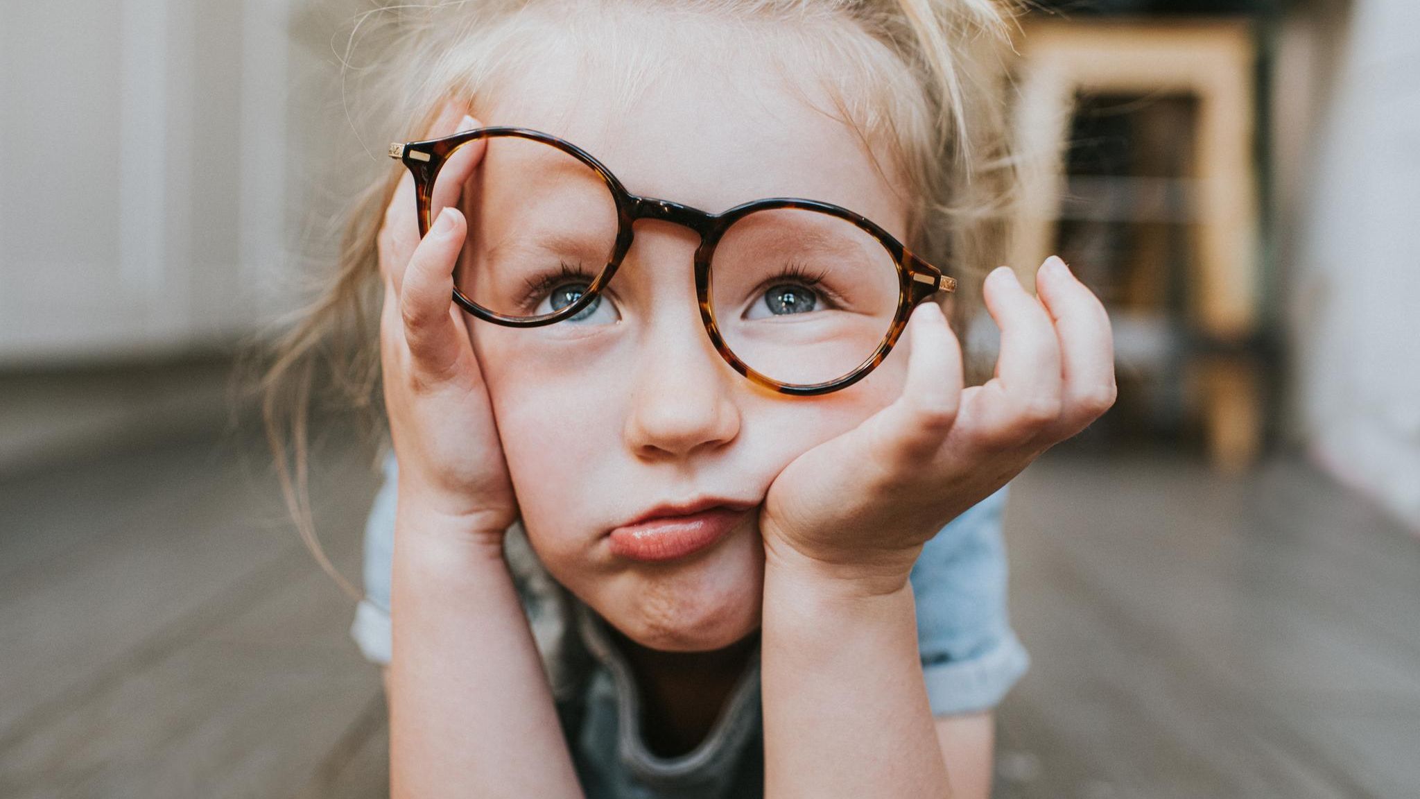 In Kind schaut geleingweilt mit verrutschter Brille an der Nase