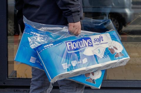 Mann trägt Packungen mit Toilettenpapier