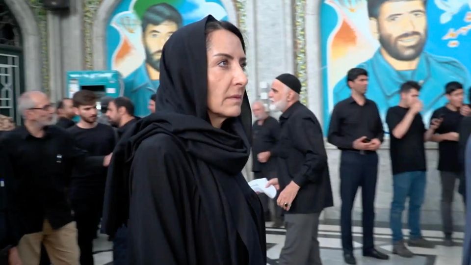 Gefahr in Teheran: Reporterin gerät ins Visier des Regimes Reporterin steht verhüllt in schwarzer Kleidung in Teheran zwischen Menschen