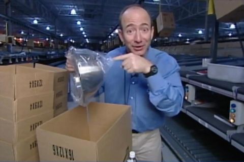 Jeff Bezos steht im Amazon Lager 1995 und hält eine silberne Schüssel in die Kamera