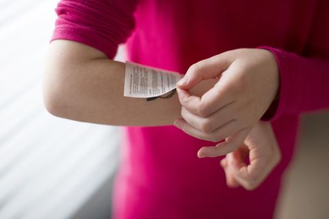 Human applying temporary tattoo to arm, cropped