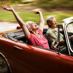 Ein älteres Paar fährt mit einem offenen Cabrio