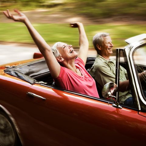 Ein älteres Paar fährt mit einem offenen Cabrio