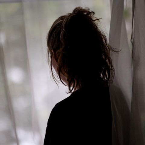 Die Konturen einer Frau sind vor einem Fenster zu sehen – Symbolbild Alleinlebende und Einsamkeit