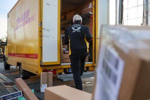 Eine Mitarbeiterin der Deutschen Post belädt ihr Fahrzeug mit Päckchen und Paketen