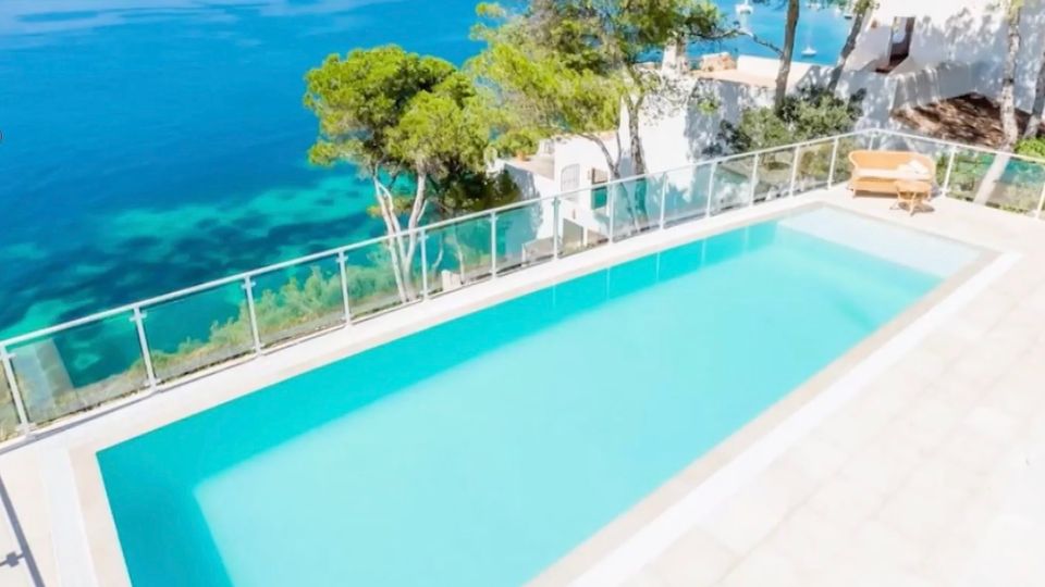 Urlaubsbetrug auf Mallorca: Familie zahlt 2.300 Euro für Haus, das es nicht gibt Ein Pool grenzt an das türkis-blaue Meer an Mallorcas Küste.