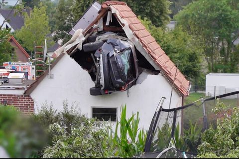 Ein Auto steckt in der Hauswand eines Einfamilienhaus in ein paar Metern Höhe.