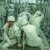 Wanderarbeiterinnen und -arbeiter sitzen in der Umkleidekabine in grünen Anzügen