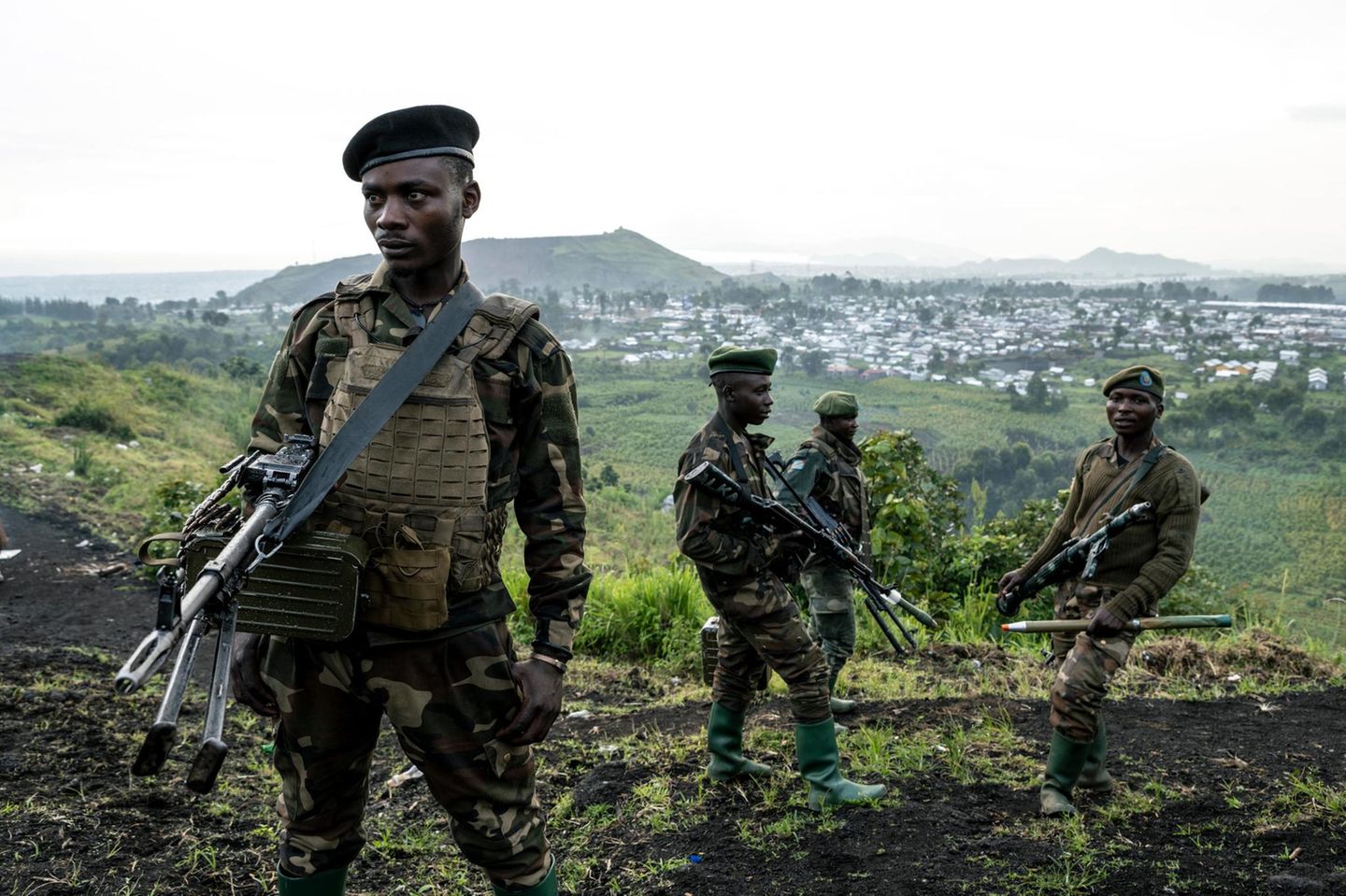 Mehr als Zahlen Soldaten stehen in Millitäruniform mit Gewehren auf einem Hügel. Im Hintergrund sieht man eine Stadt