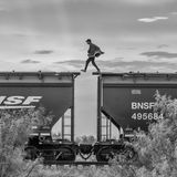 Person läuft von Wagon zu Wagon auf den Dächern eines Zuges