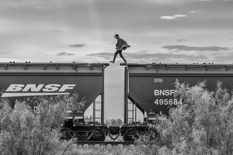 Person läuft von Wagon zu Wagon auf den Dächern eines Zuges