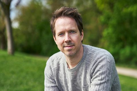 Christian Wunderlich blickt in die Kamera. Er hat kurze braune Haare und trägt einen grauen Pullover