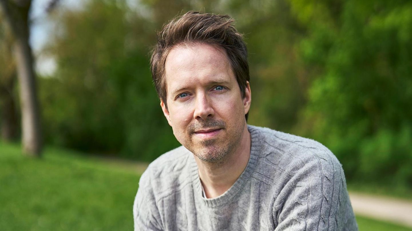 Christian Wunderlich blickt in die Kamera. Er hat kurze braune Haare und trägt einen grauen Pullover