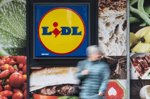 Eine Frau steht vor dem Schild einer Lidl-Filiale
