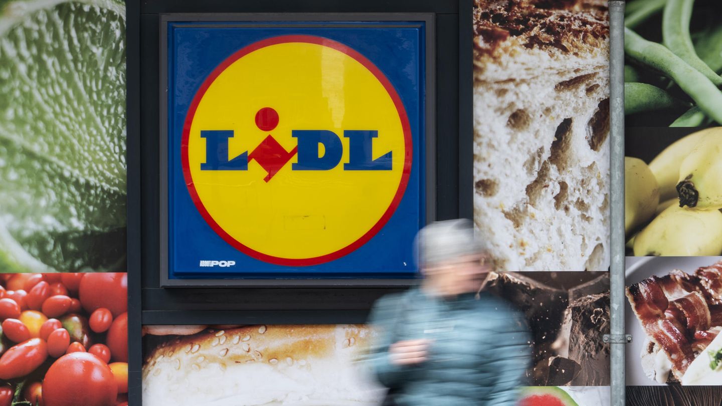 Eine Frau steht vor dem Schild einer Lidl-Filiale