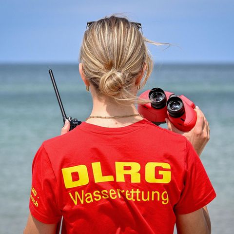 Ostsee Frau mit DLRG-Shirt und Fernglas am Strand