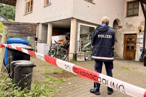 Ein Polizist steht vor dem heruntergekommenen Haus in Zwiesel, in dem drei Menschen getötet wurden