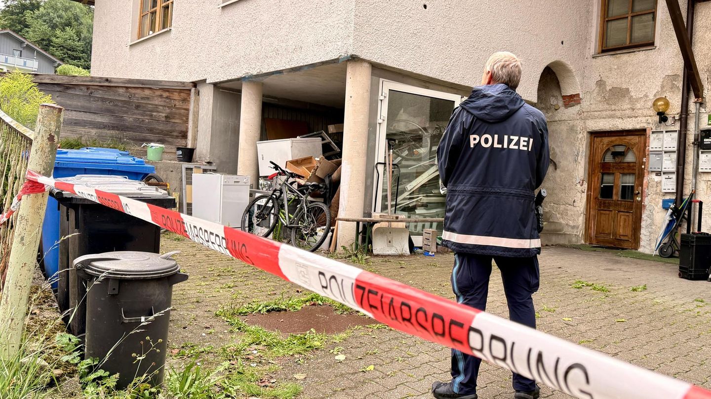 Ein Polizist steht vor dem heruntergekommenen Haus in Zwiesel, in dem drei Menschen getötet wurden
