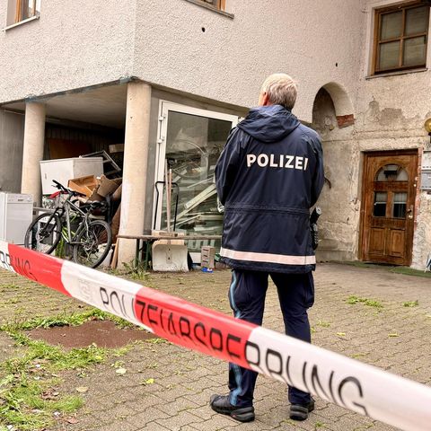 Ein Polizist steht vor dem heruntergekommenen Haus in Zwiesel, in dem drei Menschen getötet wurden