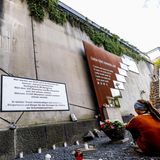 Eine junge Frau sitzt auf dem Boden an der Gedenkstätte für die Opfer des Loveparade-Unglücks