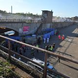 Rettungskräfte und Polizisten stehen am Tunnelausgang der Loveparade in Duisburg