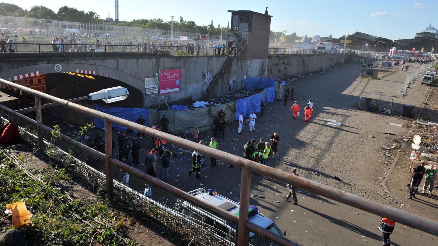 Rettungskräfte und Polizisten stehen am Tunnelausgang der Loveparade in Duisburg