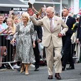 Königin Camilla und König Charles bei einem Besuch in Newmarket. Der König winkt dem Volk zu