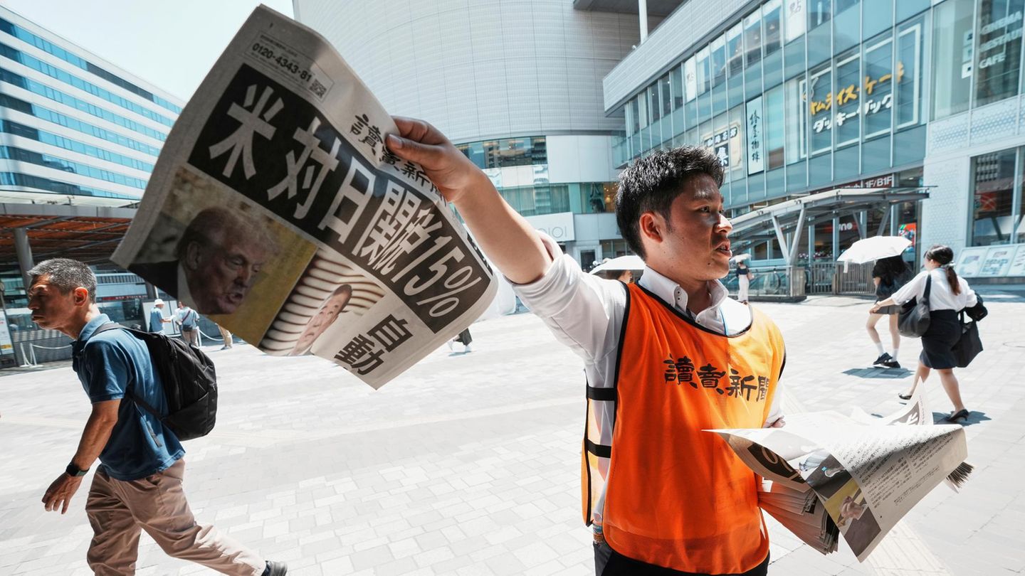 Ein Zeitungsverkäufer mit einem Titelblatt zum Handels-Deal zwischen USA und Japan