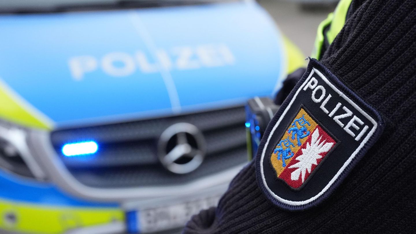 Ein Polizist aus Schleswig-Holstein steht vor einem Dienstwagen