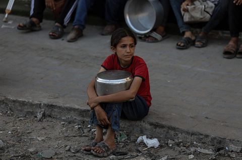 Ein Mädchen sitzt mit leerem Topf auf einem Bürgersteig in Gaza-Stadt.