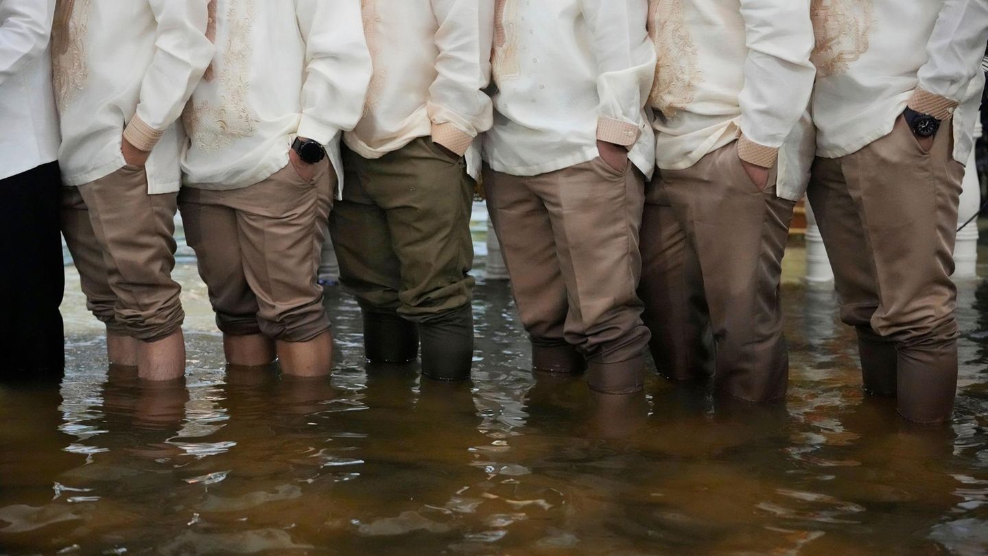 Trauzeugen und Gäste stehen knietief im Hochwasser und tragen den traditionellen Barong Tagalog