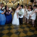 Die Frischvermählten küssen sich, während die Gäste jubeln. Auch die Brautjungfern nahmen es mit Humor: In durchnässten blauen Roben applaudierten sie dem Paar