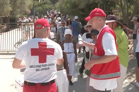 Helfer des Roten Kreuz in Athen verteilen Wasser an die Menschen.