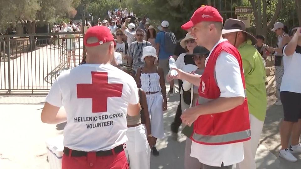 Helfer des Roten Kreuz in Athen verteilen Wasser an die Menschen.