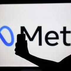 Der Schatten einer Frau mit Smartphone liegt vor dem Logo von Meta, dem Mutterkonzern von Facebook und Instagram