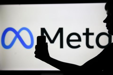 Der Schatten einer Frau mit Smartphone liegt vor dem Logo von Meta, dem Mutterkonzern von Facebook und Instagram