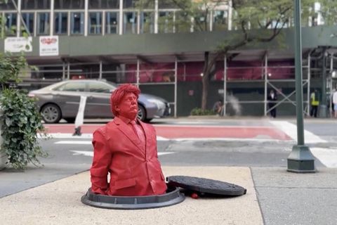 Trumps Oberkörper ragt aus einem Kanaldeckel, daneben eine Ratte