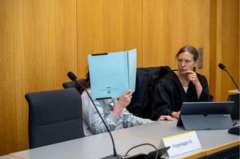 Verurteilte Mörderin Anna-Maria W. versteckt ihr Gesicht mit einer blauen Mappe. Neben ihr ihre Verteidigerin.