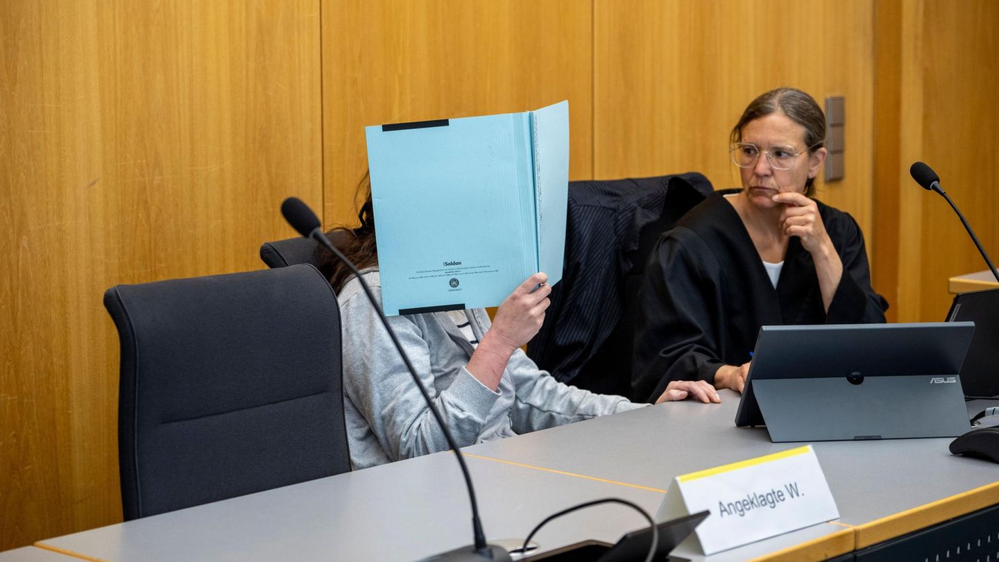 Verurteilte Mörderin Anna-Maria W. versteckt ihr Gesicht mit einer blauen Mappe. Neben ihr ihre Verteidigerin.