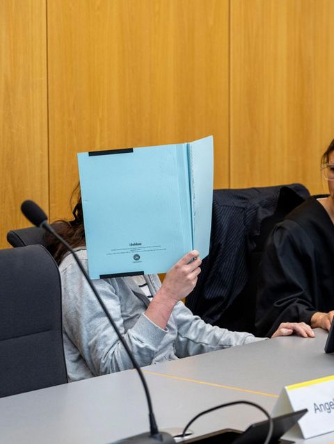 Verurteilte Mörderin Anna-Maria W. versteckt ihr Gesicht mit einer blauen Mappe. Neben ihr ihre Verteidigerin.