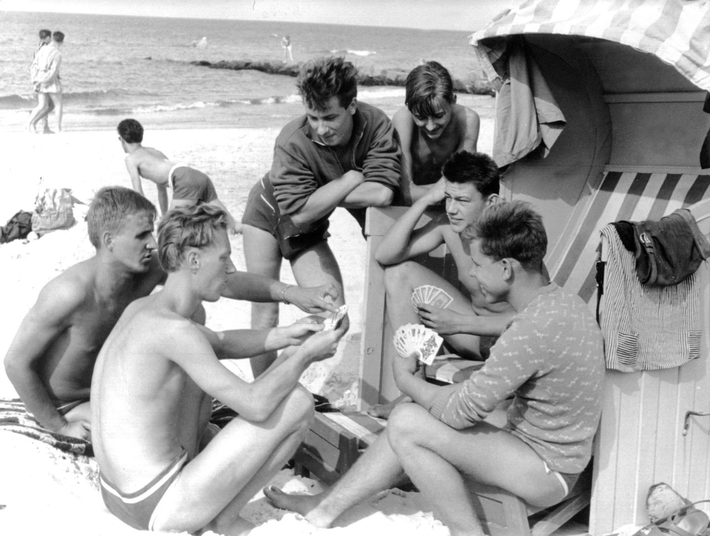 Männer am Strand um einen Strandkorb versammelt