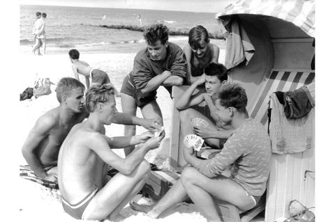 Männer am Strand um einen Strandkorb versammelt