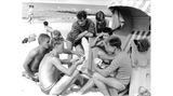 Männer am Strand um einen Strandkorb versammelt